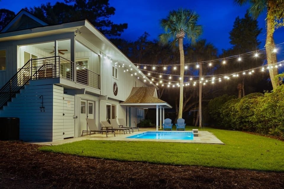 Night-time view of front yard with covered porch with the fabulous pool.