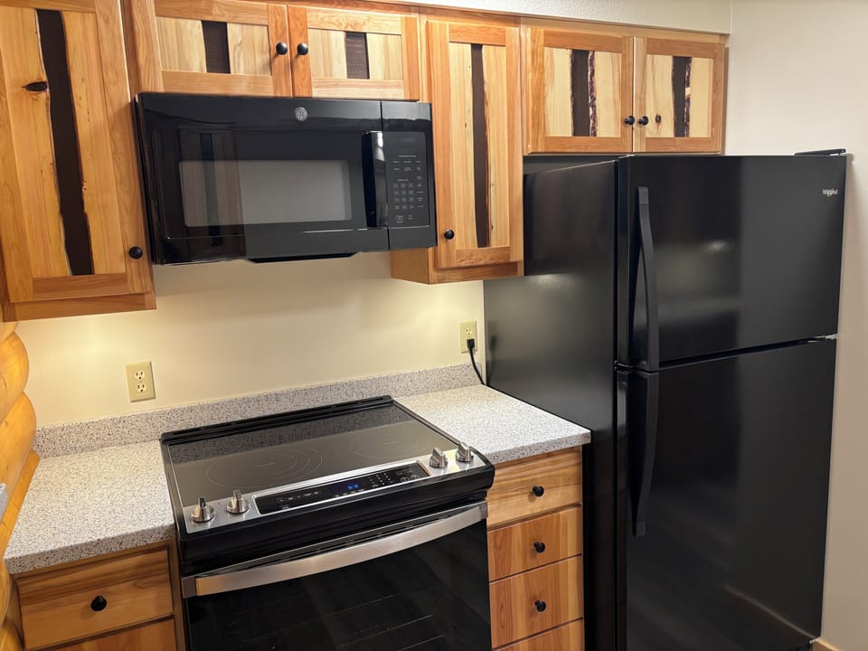 Fully equipped kitchen with fridge, stove, oven, microwave, and sink