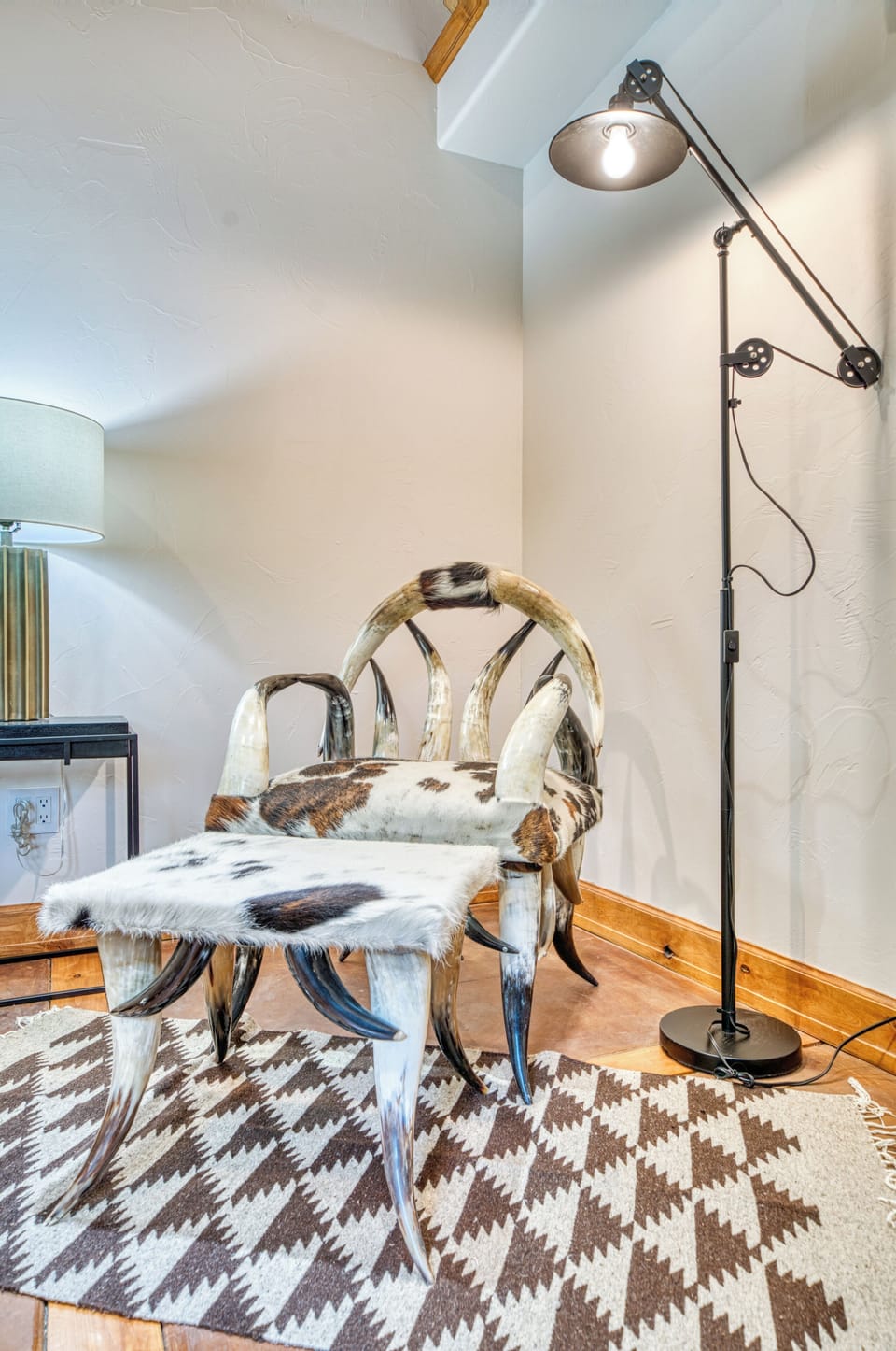 Rustic seating with cowhide upholstery and elegant lamp lighting.