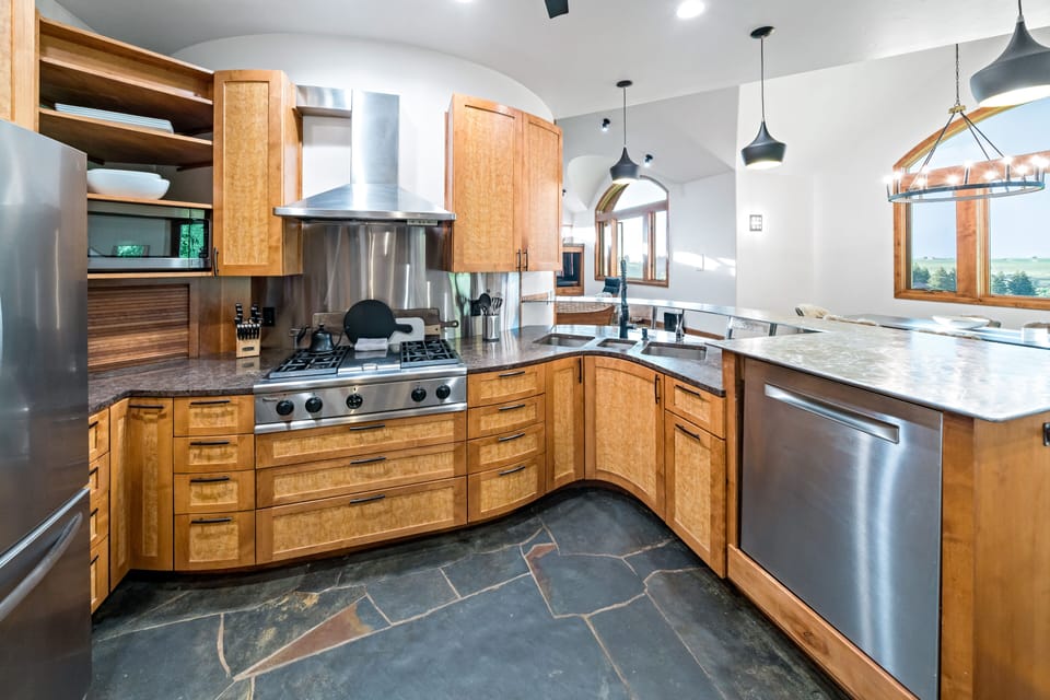 Gourmet kitchen custom cabinetry, stone floors, and stainless steel appliances