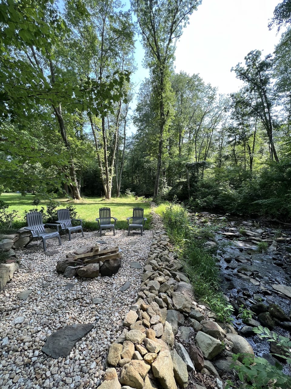 Firepit with wood adjacent to bold Piney Run.