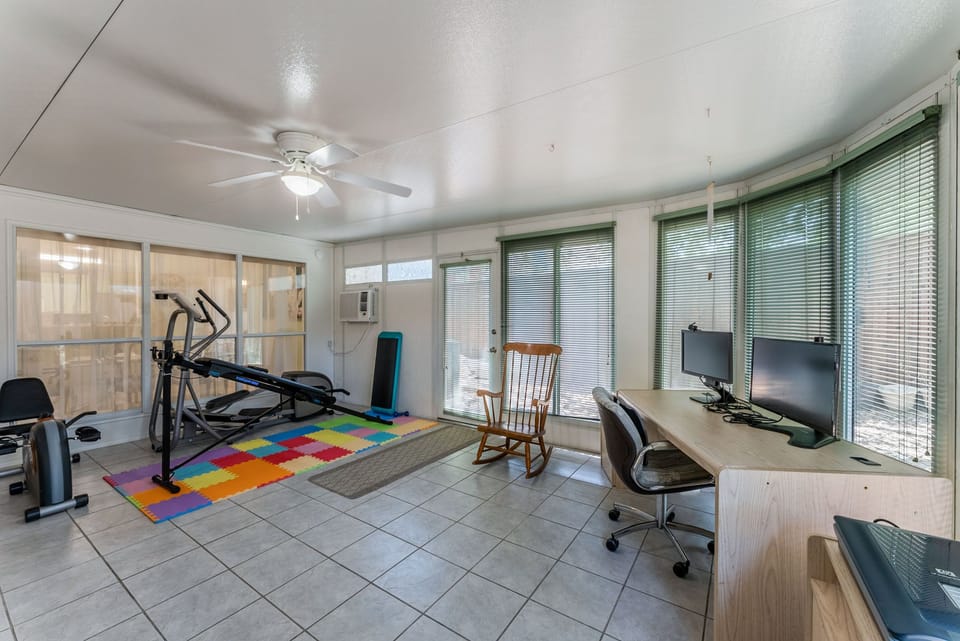Large gameroom, with workout equip, work desk, and access to backyard.