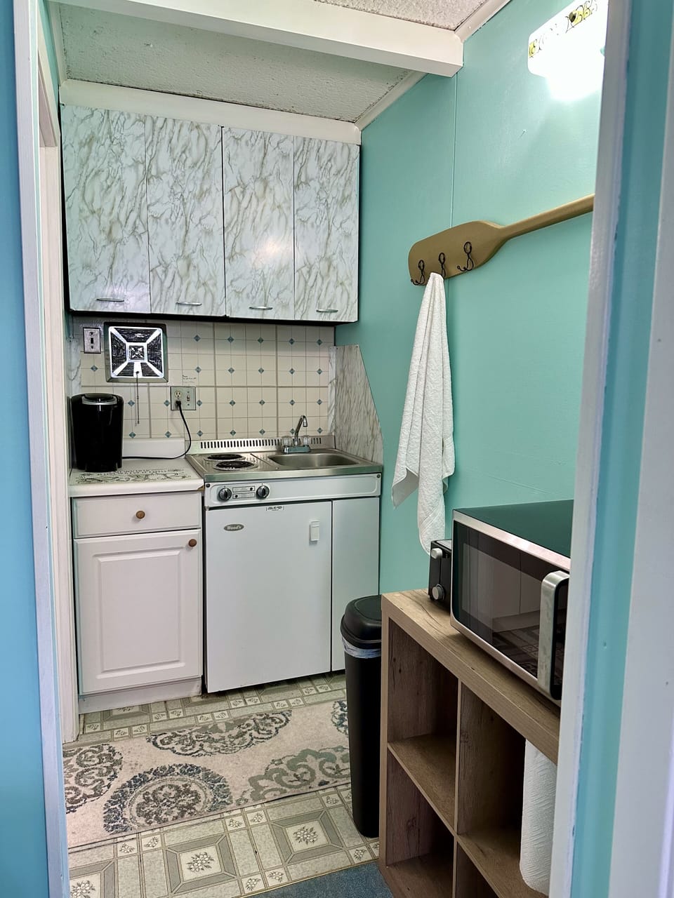 Kitchenette with small fridge, microwave, toaster, stove and Keurig machine