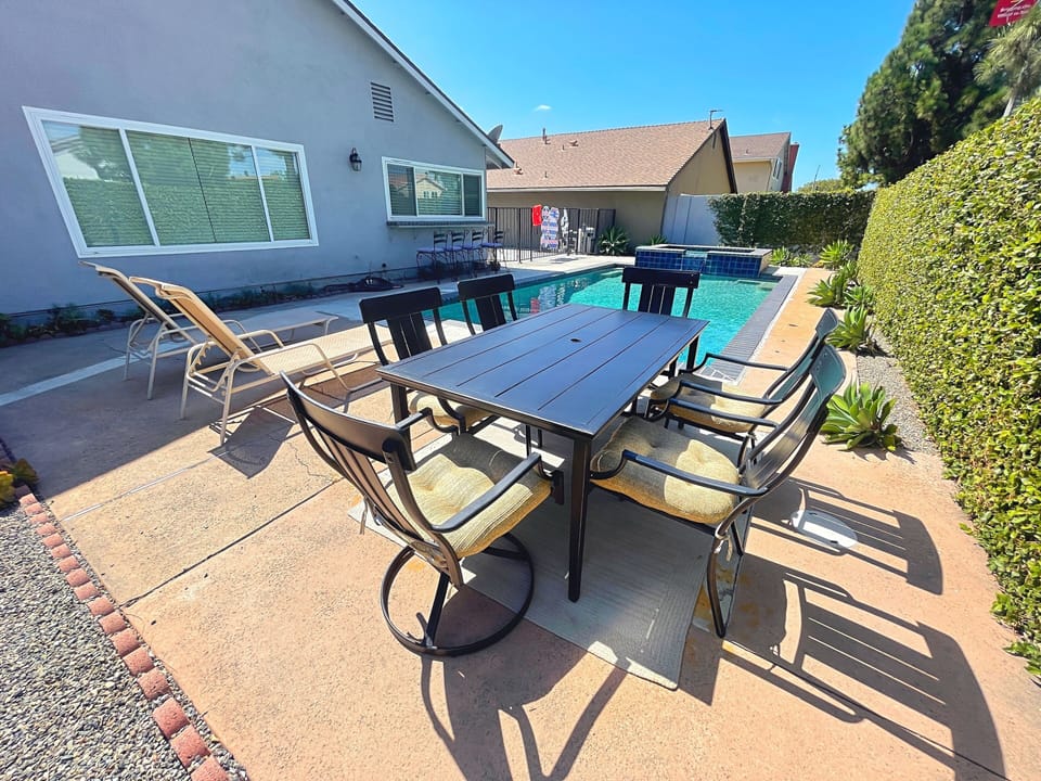Backyard with pool,  jacuzzi, outdoor dinning table and lounge pool chairs.