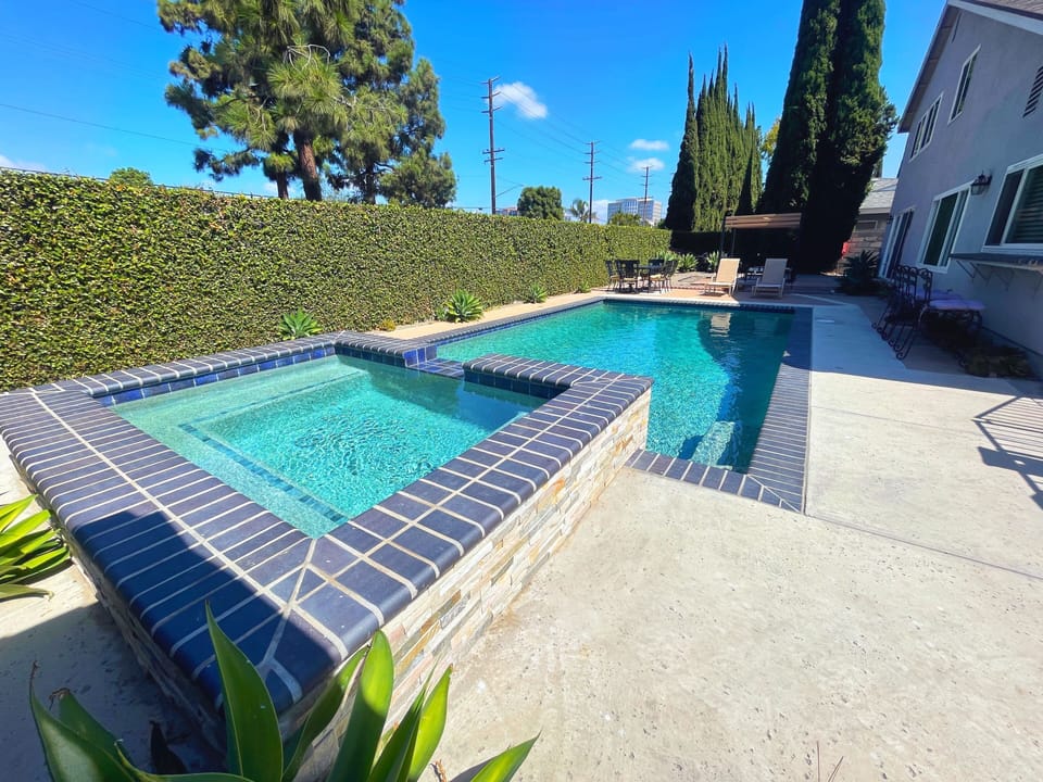 Backyard with pool,  jacuzzi, outdoor dinning table and lounge pool chairs.