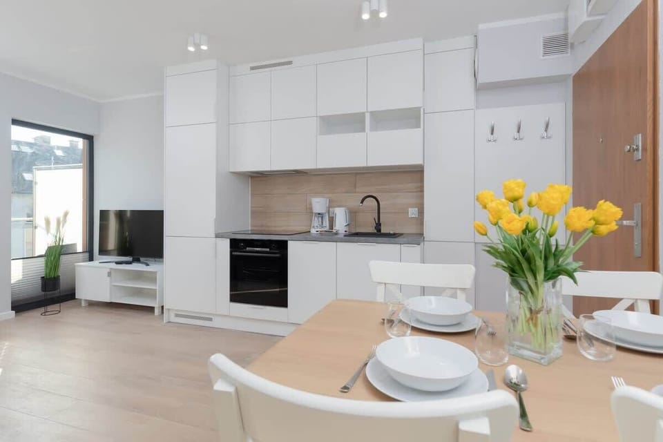 A kitchen and dining area with bright white furniture, fresh flowers, and an inviting atmosphere.
