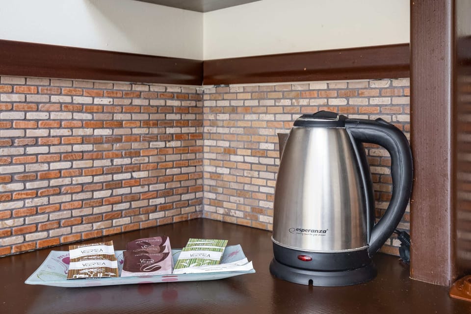 Another angle of the kitchen showing a modern kettle on the counter, with wood and brick-style tiling adding a warm, homey feel.