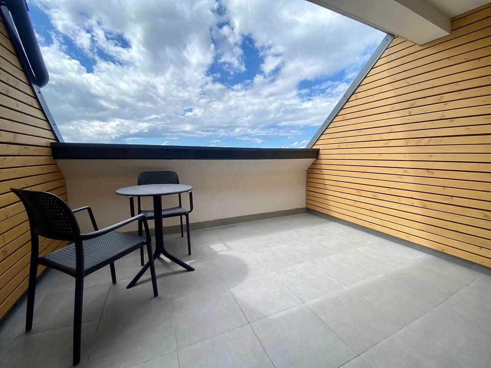 A spacious terrace with outdoor seating, wooden paneling, and stunning views of the sky and surroundings.

