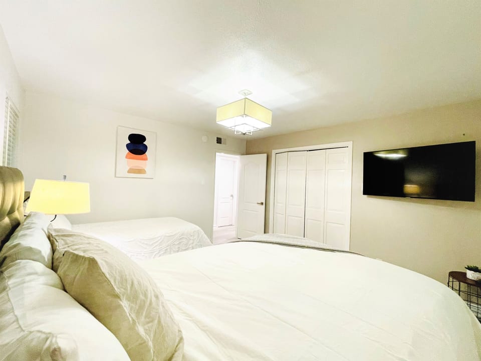 Downstairs bedroom with one queen bed and one twin bed, TV wall.