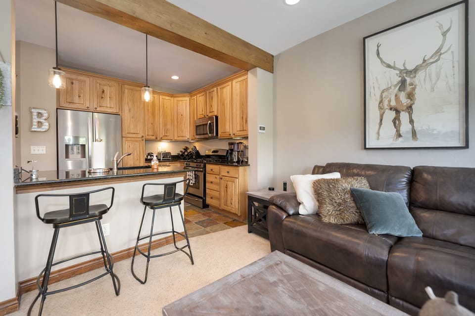 - Kitchen and living area with rustic wood cabinetry   - Open layout with breakfast bar and bar stool seating   - Great setup for casual meals and family connection