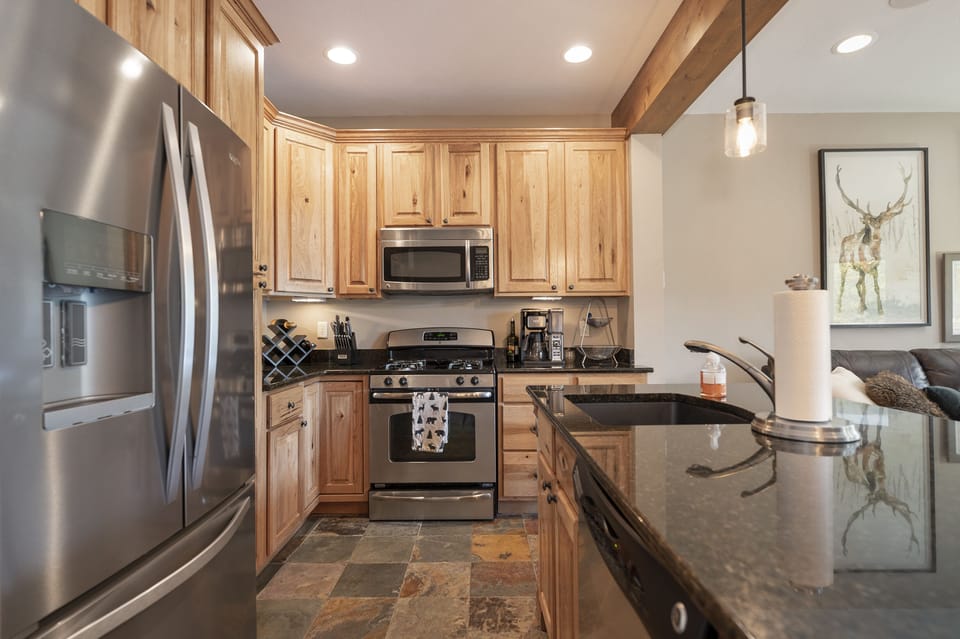 - Modern kitchen with stainless appliances and wood   - Granite counters paired with slate flooring design   - Fully equipped space perfect for cooking at home