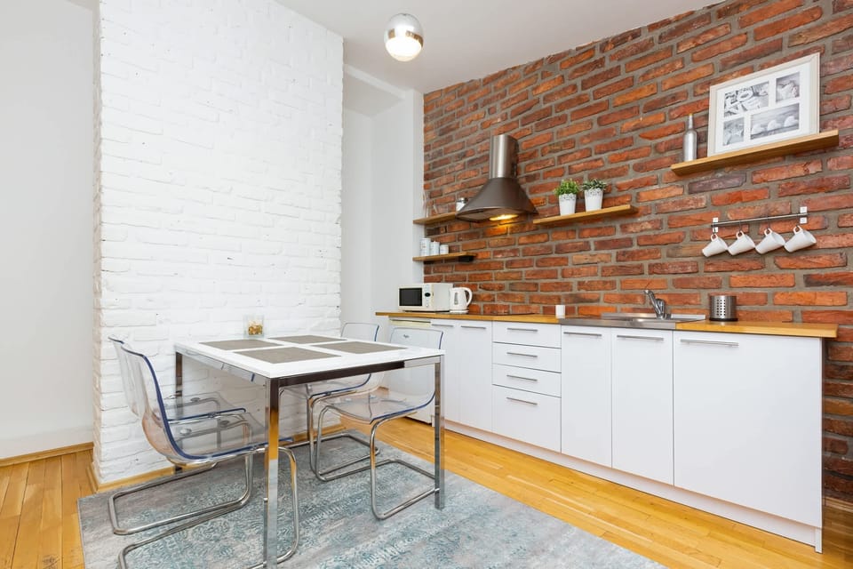 An open-plan kitchen with white cabinetry and shelves, blending functionality with industrial-style decor.
