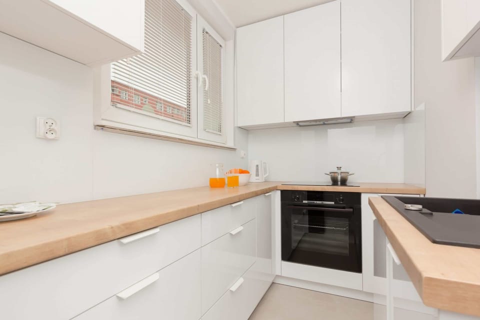 A sleek kitchen with white cabinetry, wooden countertops, and modern appliances for a fully equipped cooking space.
