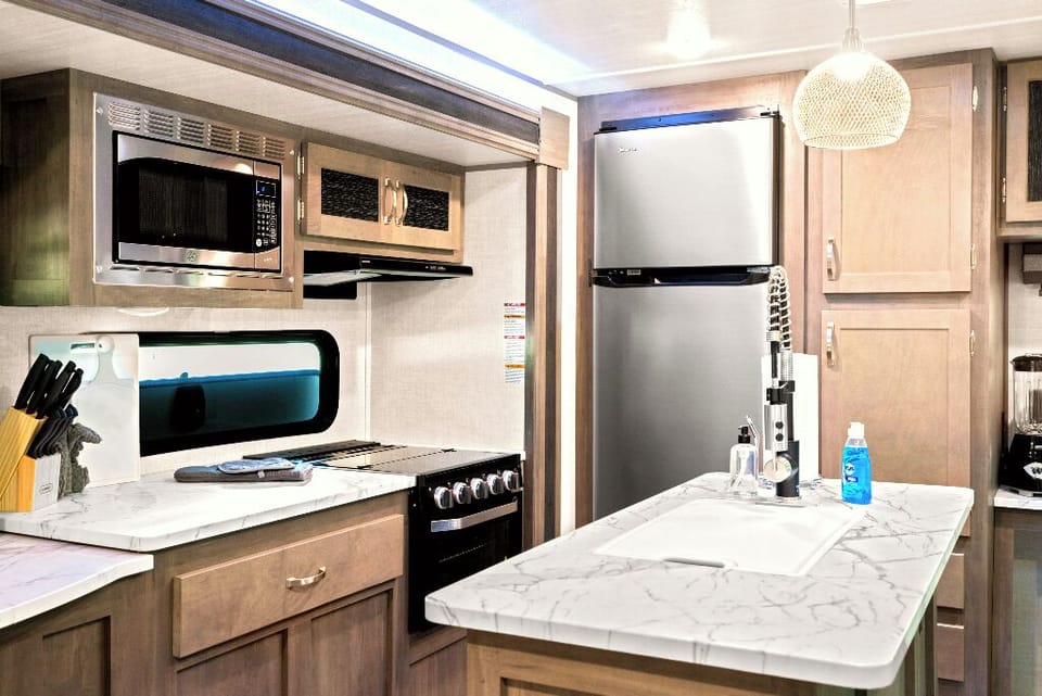 The Moto Ranch at Croom Vacation rental MX rv trailer. one bedroom 1 full bath sleeps 3. full kitchen with island sink, fridge and freezer, coffee maker, microwave, propane stove and oven, hood vent, dining table, reclining sofa chairs, retractable tv, small desk and chair