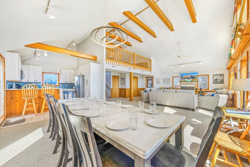 Step into this open, sun-drenched living space featuring soaring vaulted ceilings with warm wood beams, a spacious dining area, and cozy seating—perfect for gathering after a day of adventure.