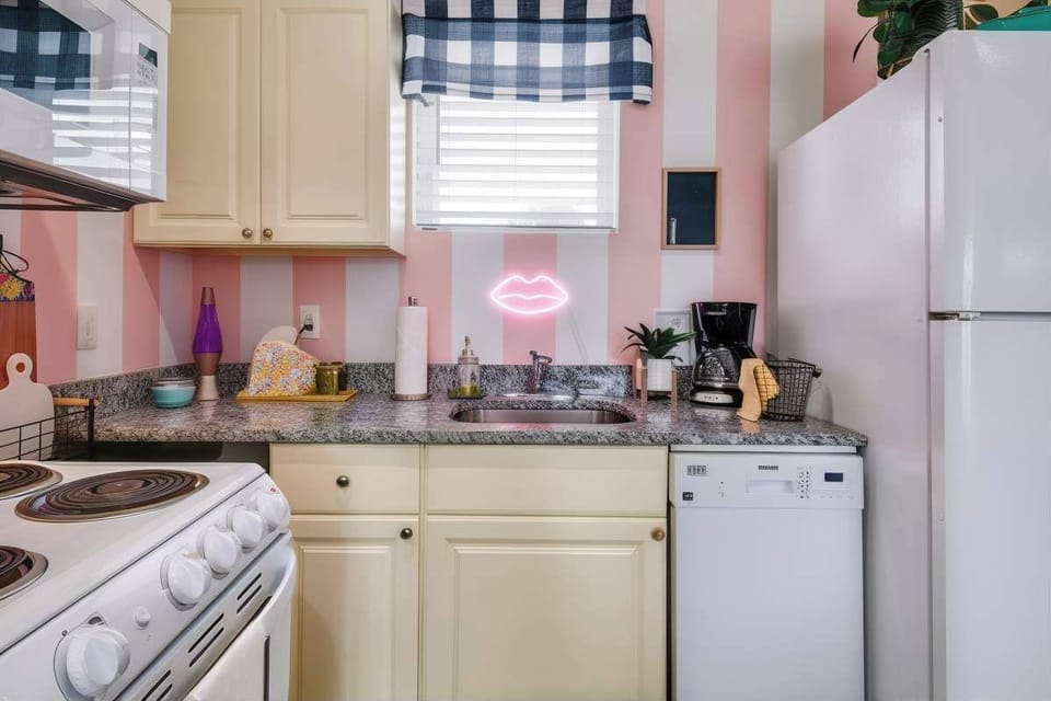Pink-striped walls, a neon lip sign, and all the appliances you need to cook for twelve. The kitchen sets the tone before you even leave for the night