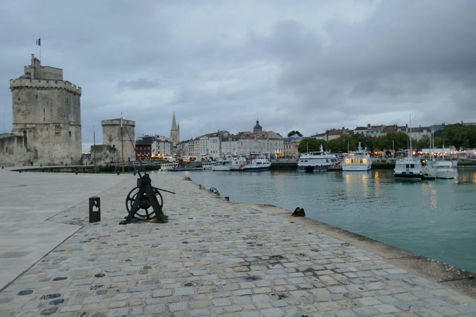 Cobblestone quayside leading toward the medieval Tour Saint-Nicolas, with a historic cannon mounted on the dock