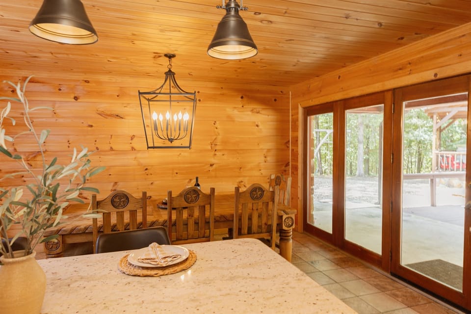 The dining area offers ample seating for family meals, surrounded by the cabin’s rustic charm.