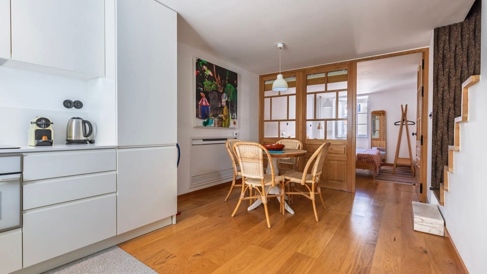 Modern white kitchen paired with a cozy wooden dining set, creating a welcoming space to enjoy meals. #ContemporaryCharm #CozyDining