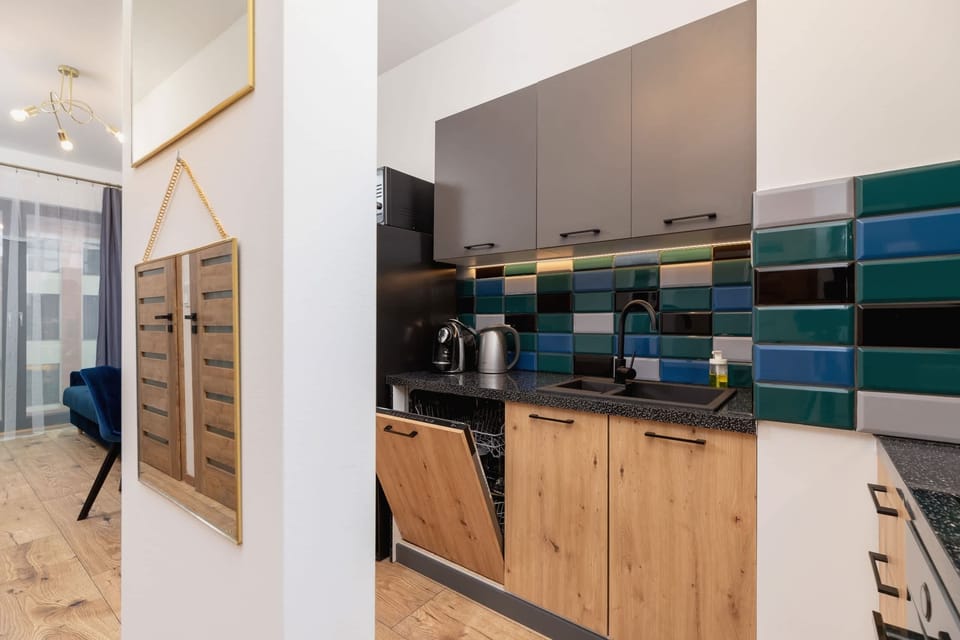 The kitchen area with sleek black appliances, wooden accents, and colorful tiles for a dynamic look.
