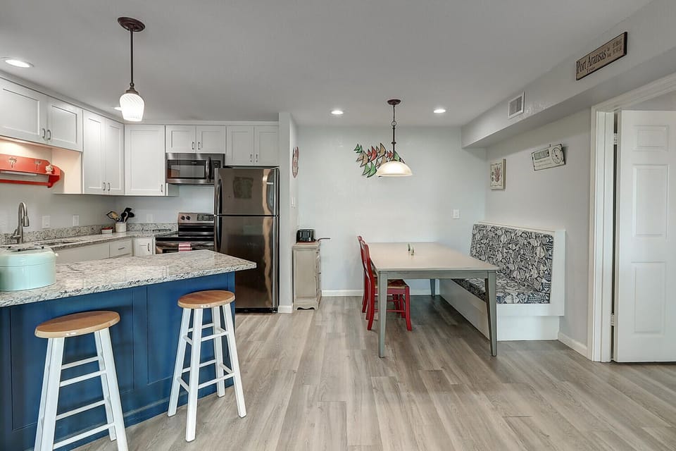 Your modern kitchen flows seamlessly into a cozy dining nook, where colorful pendant lights and stylish seating create the perfect spot for morning coffee or evening meals.