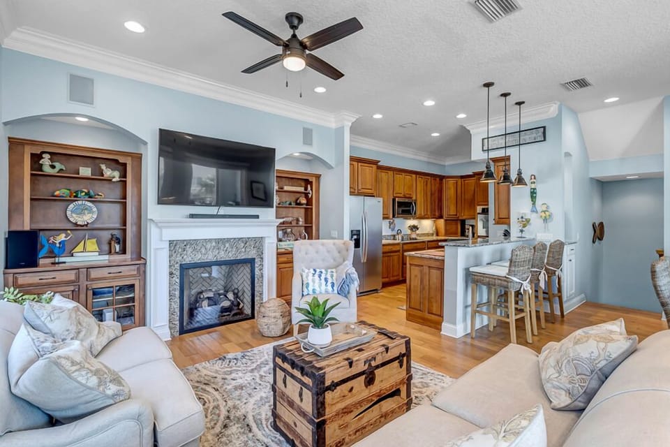 Main Living Area - - Open concept layout features a cozy living room and breakfast bar seating
- Modern fireplace and TV create a stylish entertainment area for all to enjoy
- Spacious and bright, ideal for family gatherings or group lounging