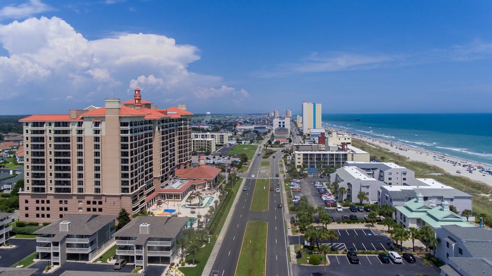 Stunning aerial view of the beachfront area showcasing modern buildings, pristine coastline, and nearby amenities in this vibrant coastal destination.