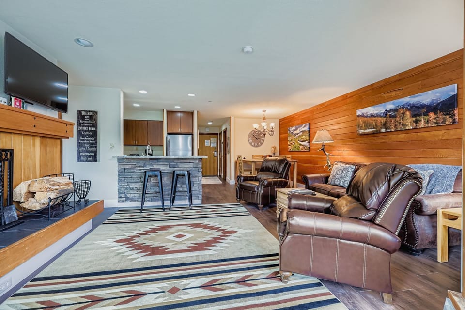 Relax in your spacious living room featuring comfortable leather seating, a cozy fireplace, and modern kitchen with breakfast bar - perfect for unwinding after your adventures.
