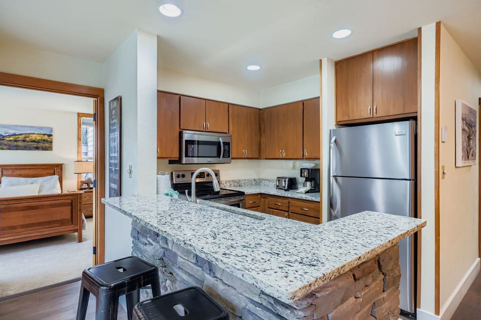 Your fully equipped kitchen features granite countertops, stainless steel appliances, and a breakfast bar where you can prepare meals and enjoy casual dining.