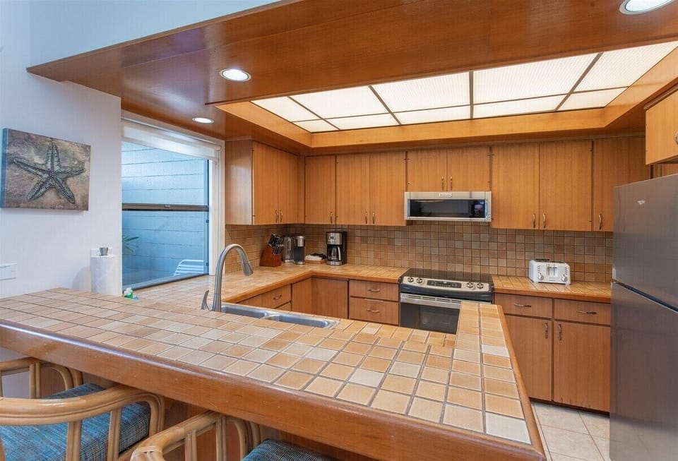 The kitchen is located next to the dining room table, and features a cozy breakfast bar with two pull up stools