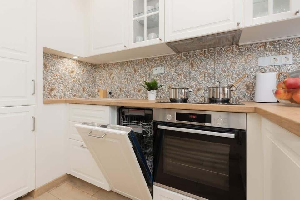A close-up of the kitchen counter with a tiled backsplash, built-in oven, and organized layout.
