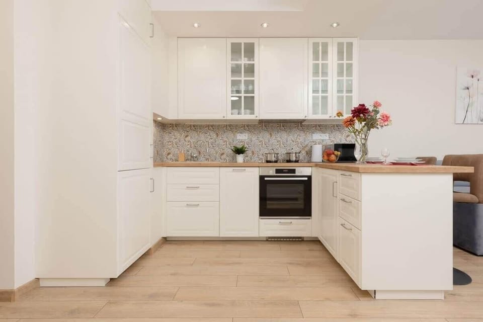 A fully equipped kitchen with white cabinetry, tiled backsplash, and ample countertop space.
