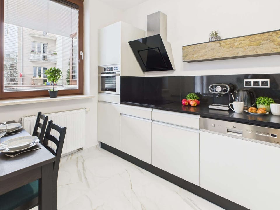 A modern kitchenette with white cabinetry, stainless steel appliances, and ample counter space for meal preparation.