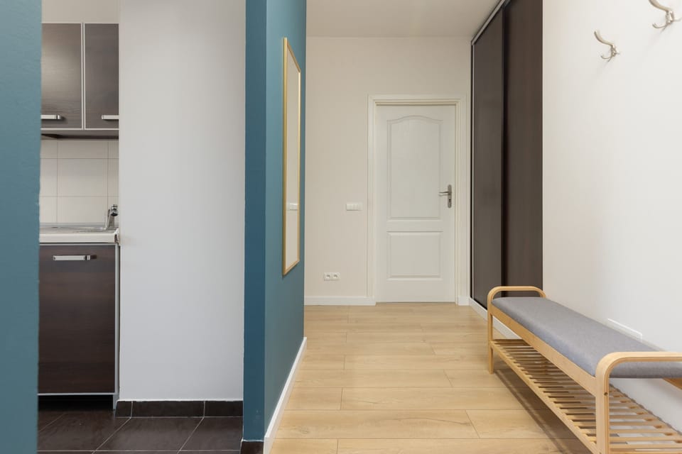 A hallway with a blue accent wall, built-in storage, and wooden flooring, creating a modern and welcoming entrance.

