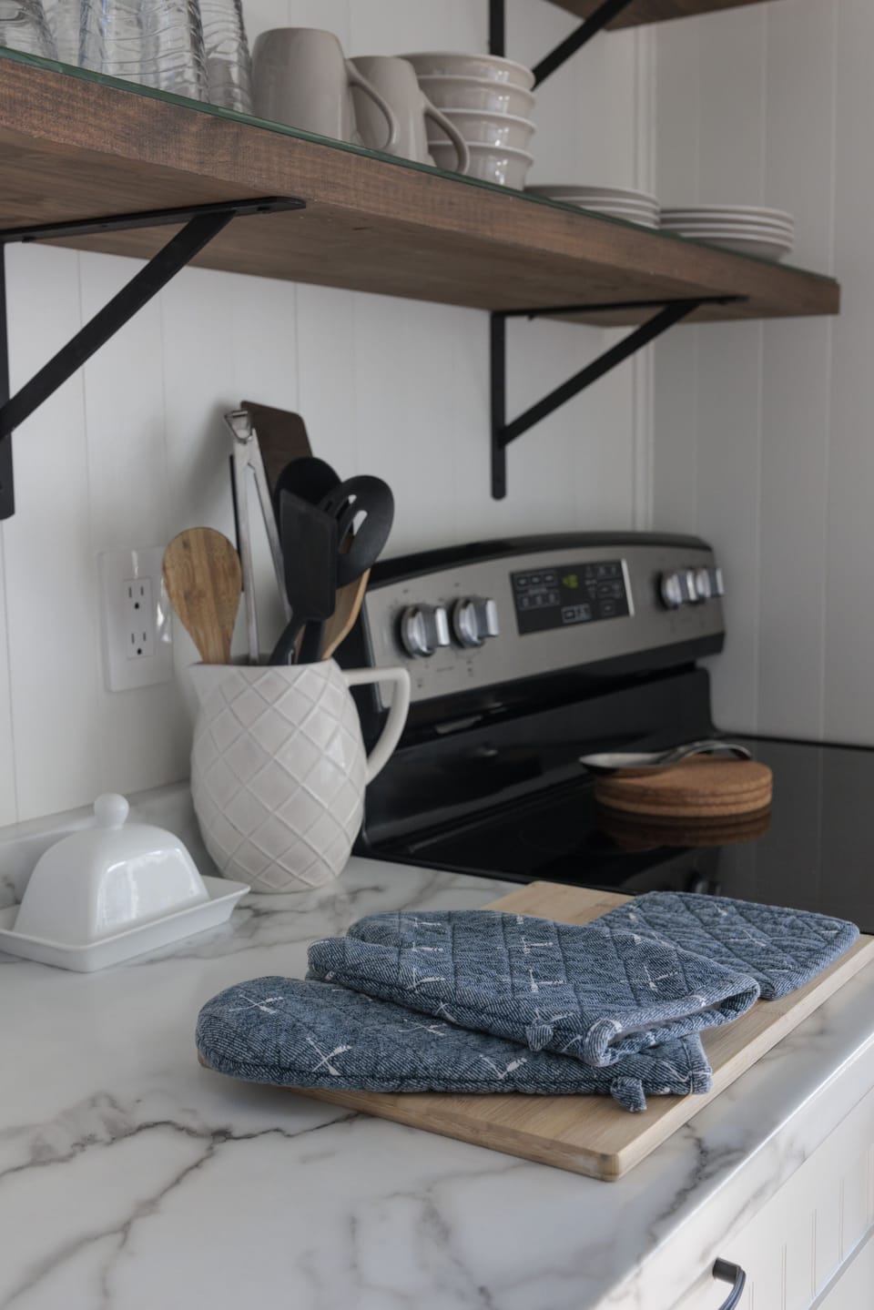 Cutting board, oven mitts, and cooking utensils. Sharp knives are in the drawer.
