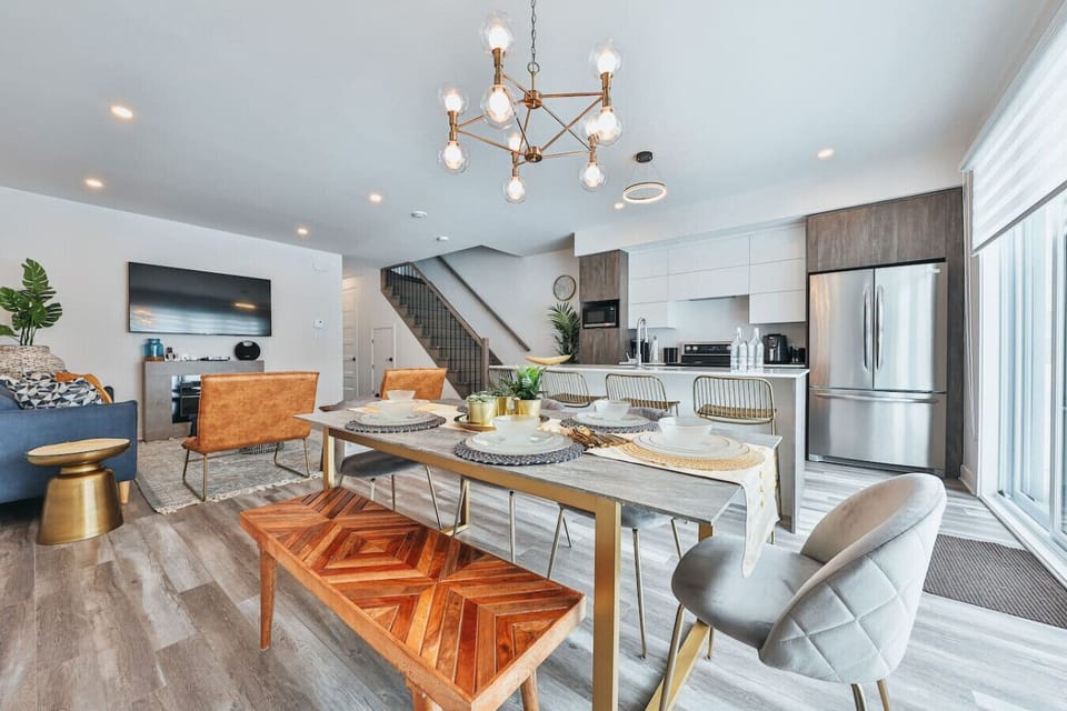 Open-concept main floor connecting the living room, dining table, and gourmet kitchen with stainless steel fridge.