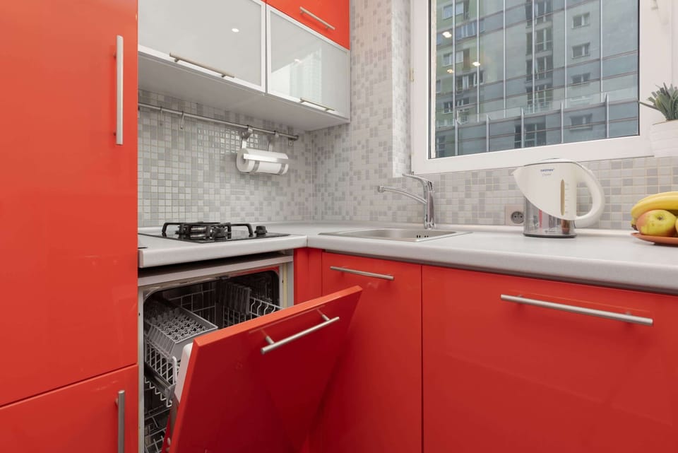 Another angle of the red kitchen, highlighting the storage and countertop space with views of the cityscape through the window.
