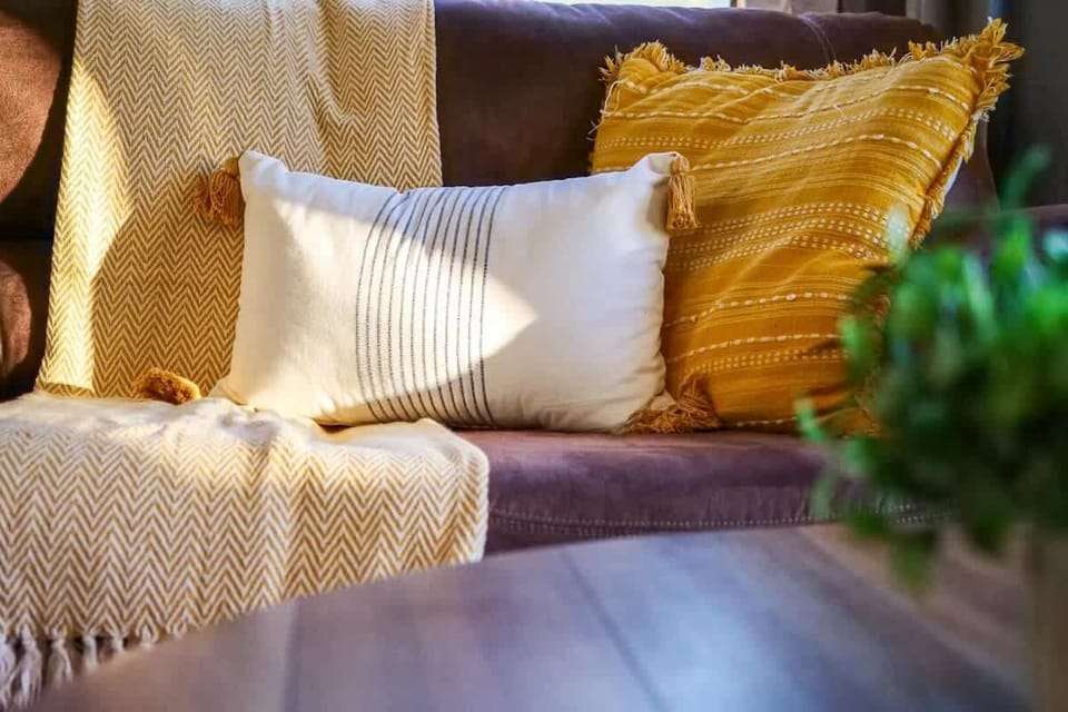  - Cozy closeup of pillows and throw on soft brown sofa   - Inviting textures and warm colors enhance guest comfort   - Relaxing details designed for restful living moments
