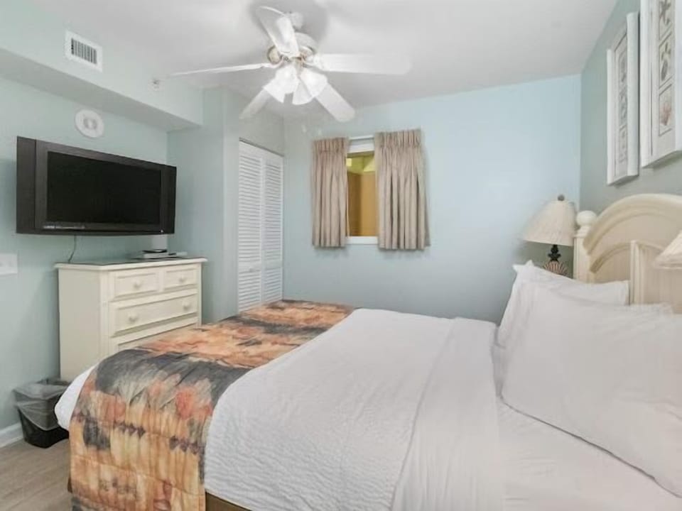 Rest peacefully in your serene bedroom featuring calming blue walls, crisp white linens, and modern amenities for ultimate relaxation.