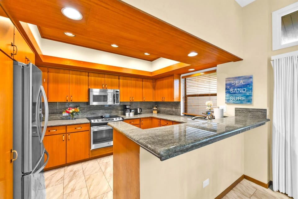 Fully equipped kitchen with bar seating and rich wood cabinetry.