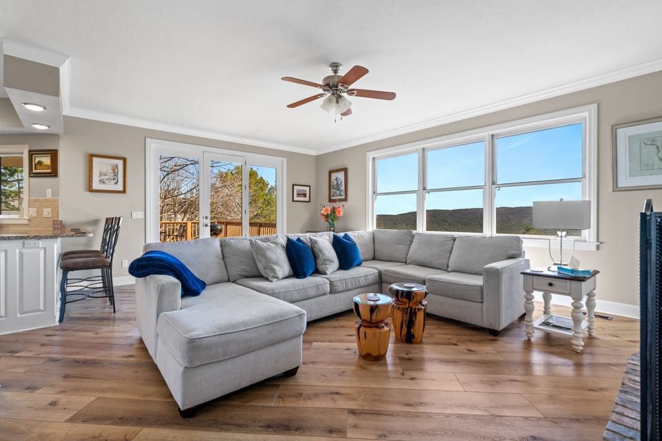 Living room with large sectional and big windows to enjoy the amazing view.