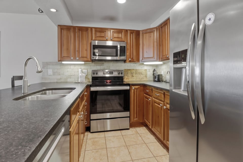 Cook your favorite meals in this fully equipped kitchen with stainless appliances, granite counters, and warm wood cabinets.
