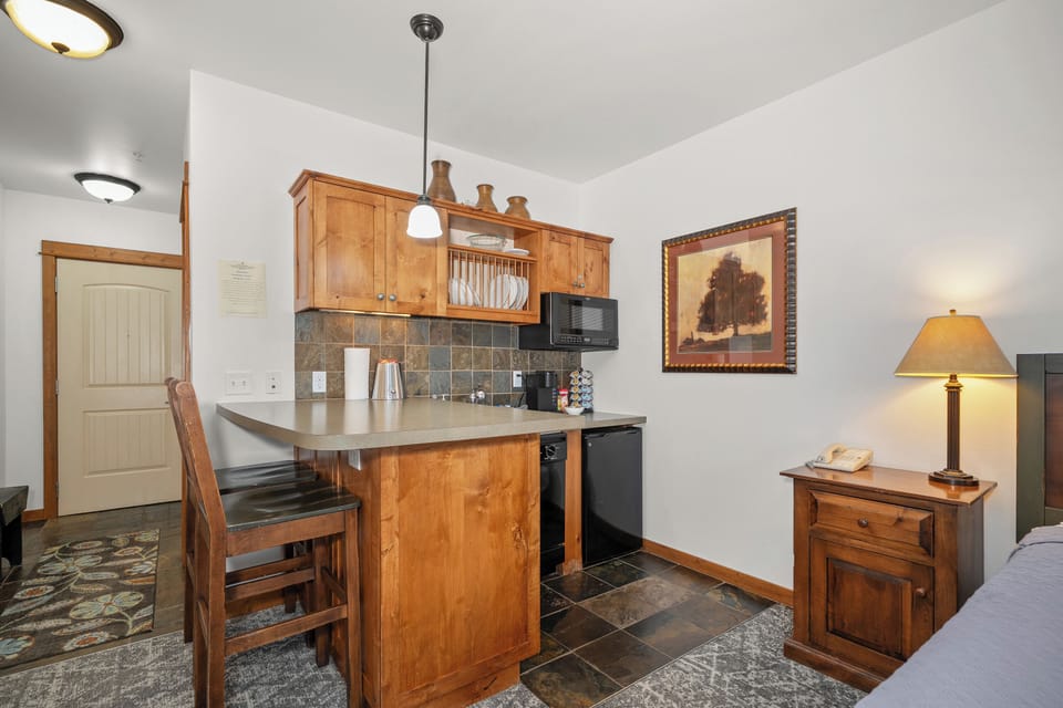 Cozy kitchenette with breakfast bar, mini fridge, and rustic wood finishes