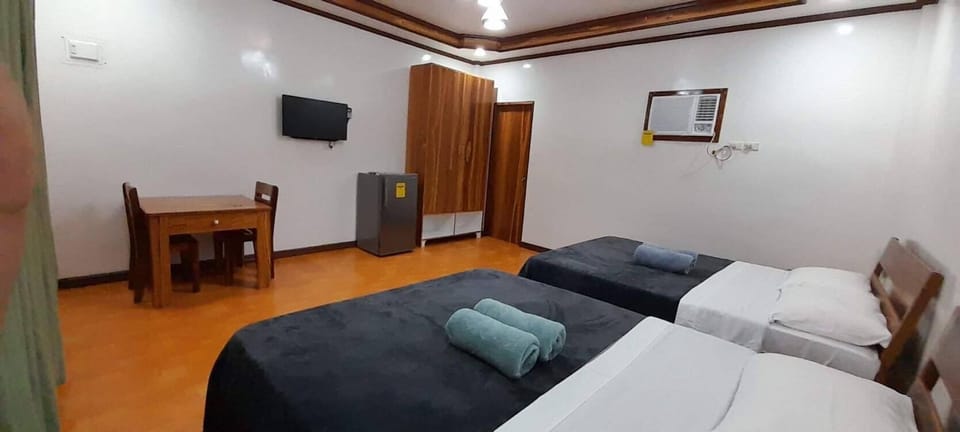 2 Queen Bed interior, table & chairs, TV, Fridge, stand-up closet, and AC.