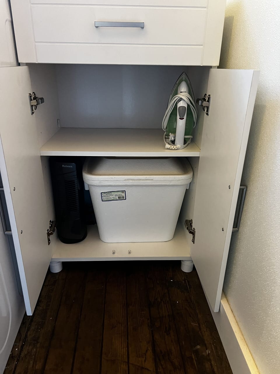 Iron, portable fan and cooler in cabinet. Laundry pods in drawer