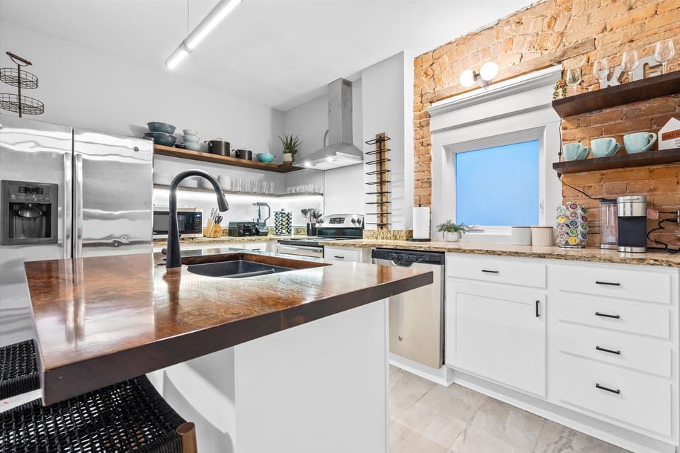 Remodeled kitchen with exposed brick, stainless steel appliances and an enhanced coffee bar. 