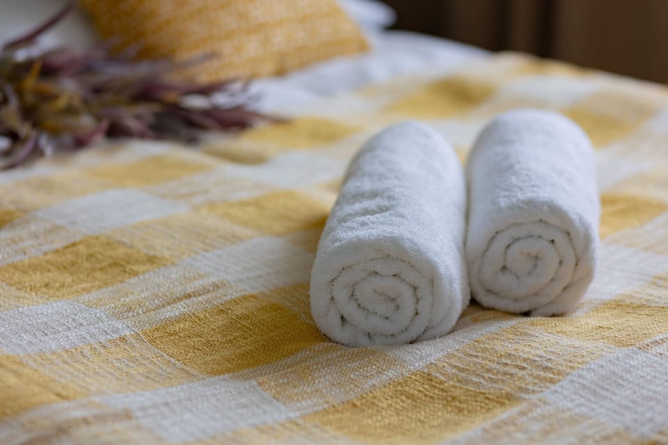 Neatly rolled towels placed on a checkered yellow throw, emphasizing guest comfort and attention to detail.
