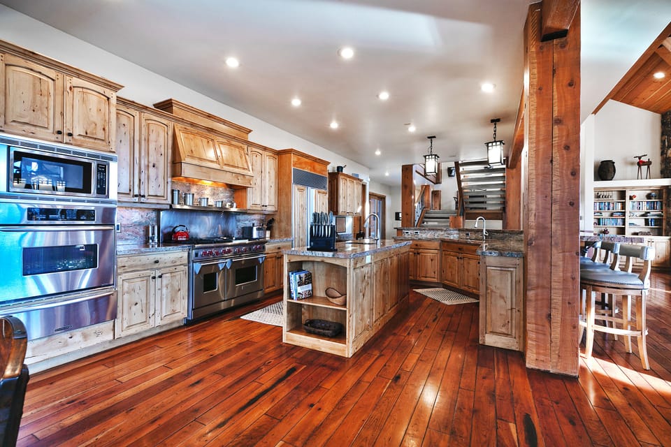 A chef's kitchen with two kitchen islands, wooden cabinetry, granite countertops, and stainless steel state of the art appliances.