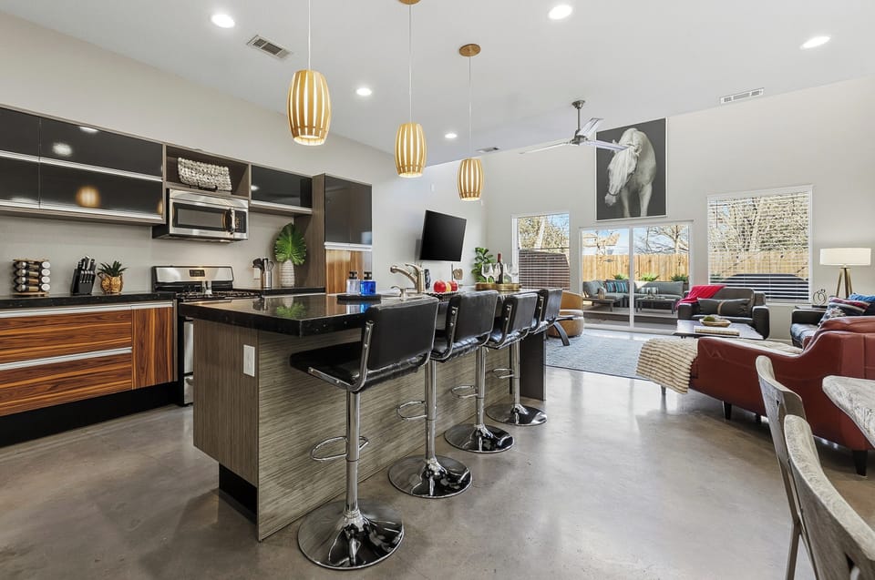 Fully equipped kitchen with sleek black countertops and a large breakfast bar with seating for 4 for casual dining.