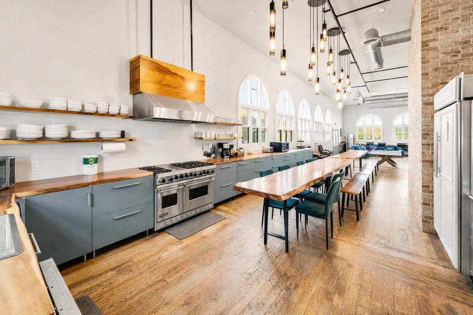 Spacious Open-Concept Kitchen with Long Dining Table, Premium Appliances, and Ample Seating — Designed for Shared Meals and Effortless Entertaining